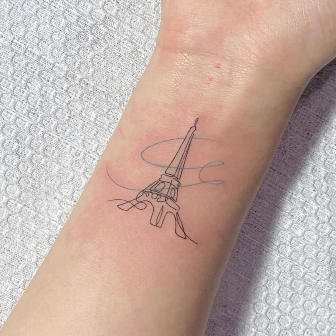 Minimalist tattoo of the Eiffel Tower on a wrist.
