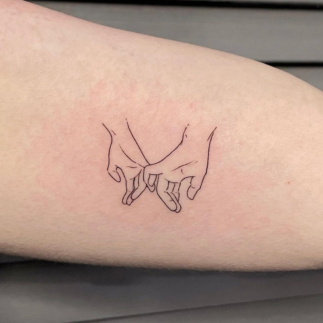 Line art tattoo of two hands holding fingers.