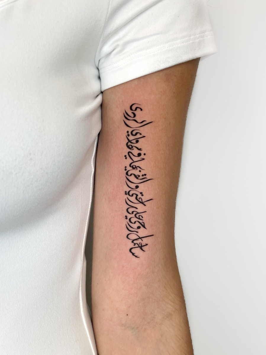 Black ink Arabic tattoo on a person's arm