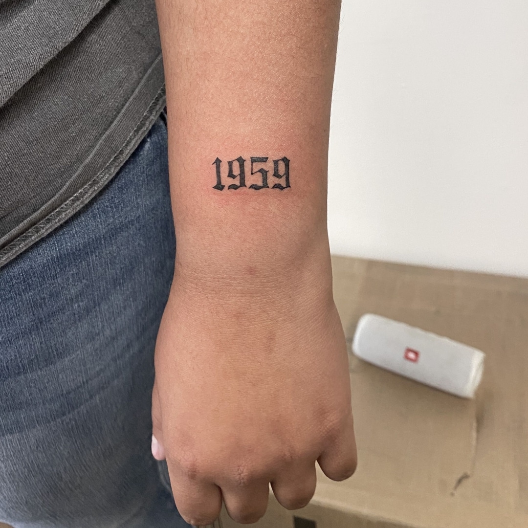 A tattoo of '1959' on a person's forearm.