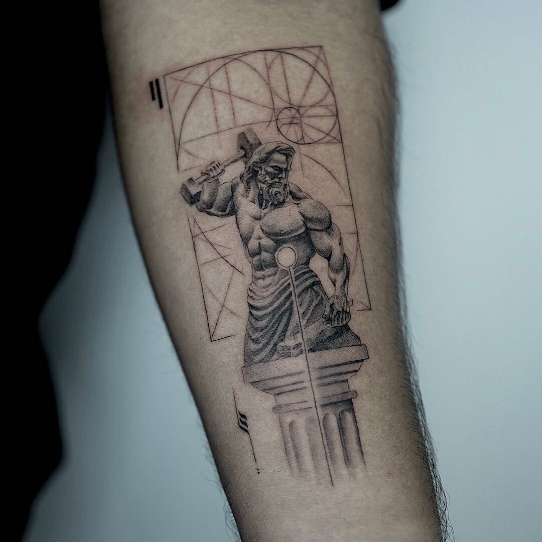 Detailed tattoo of a muscular figure resembling a Greek god on an arm.