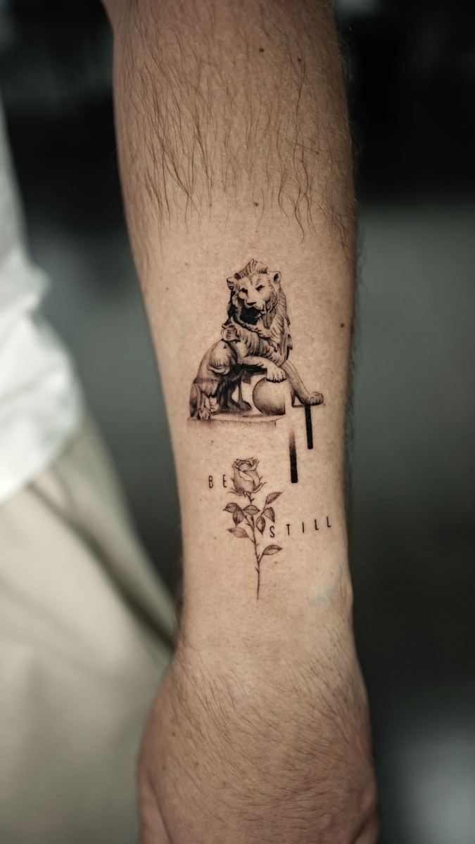 Tattoo of a lion and a rose with text on forearm