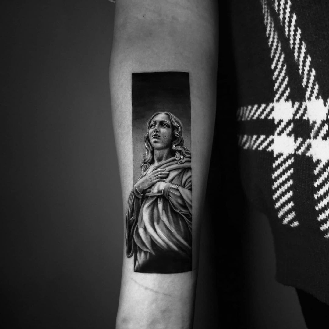 Black and white tattoo of a serene figure on an arm