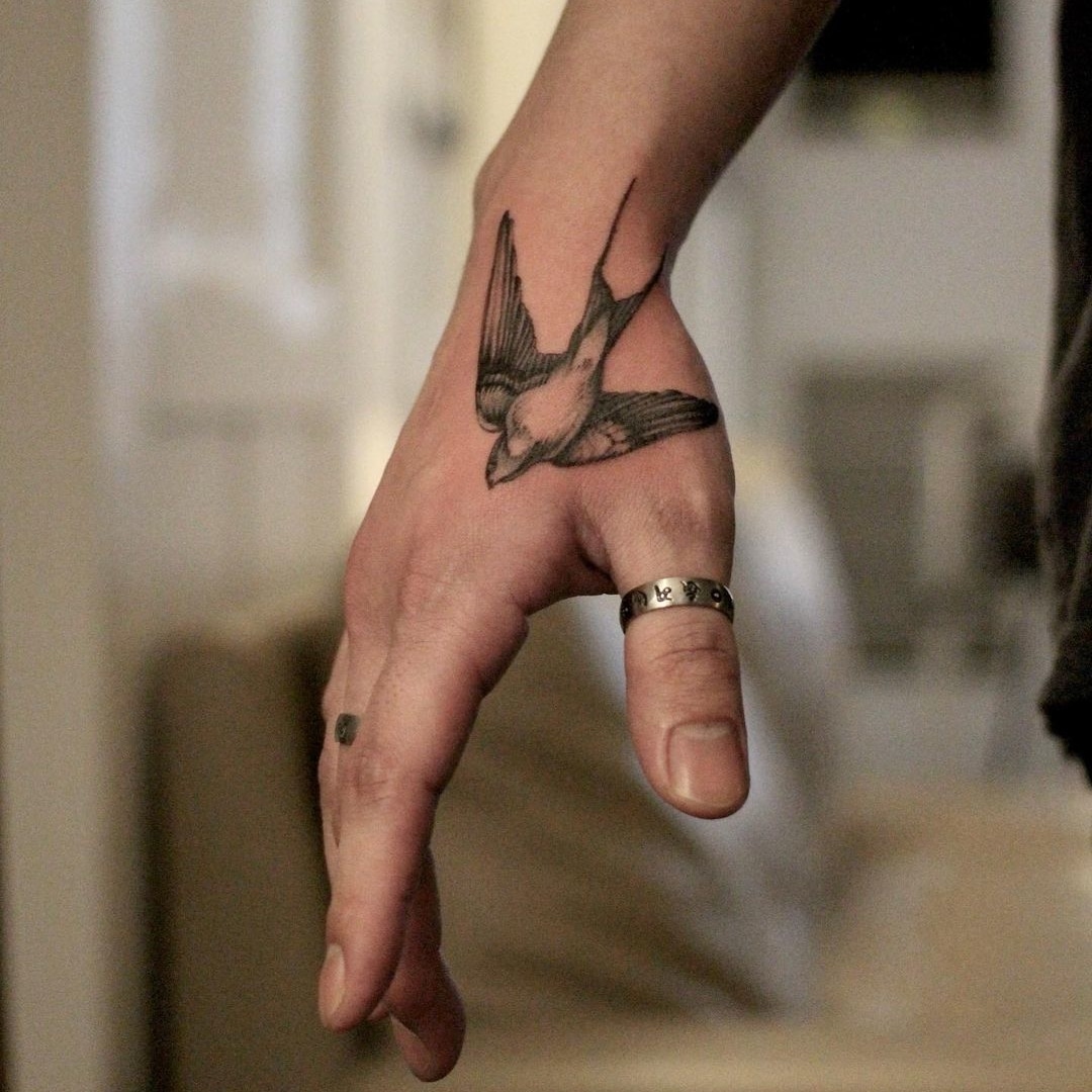 Tattoo of a bird on hand with ring and soft background