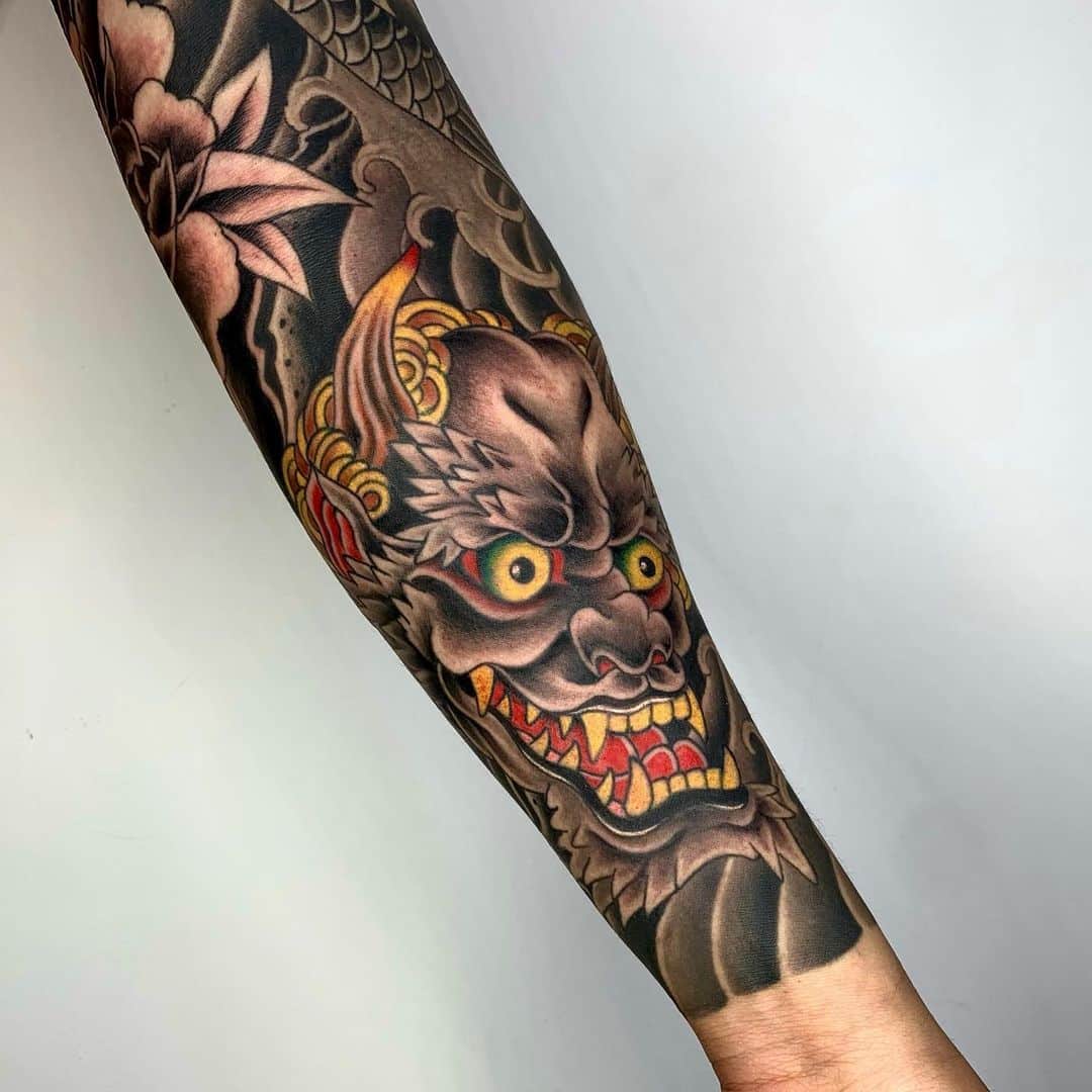 Colorful tattoo of a fierce demon on a forearm