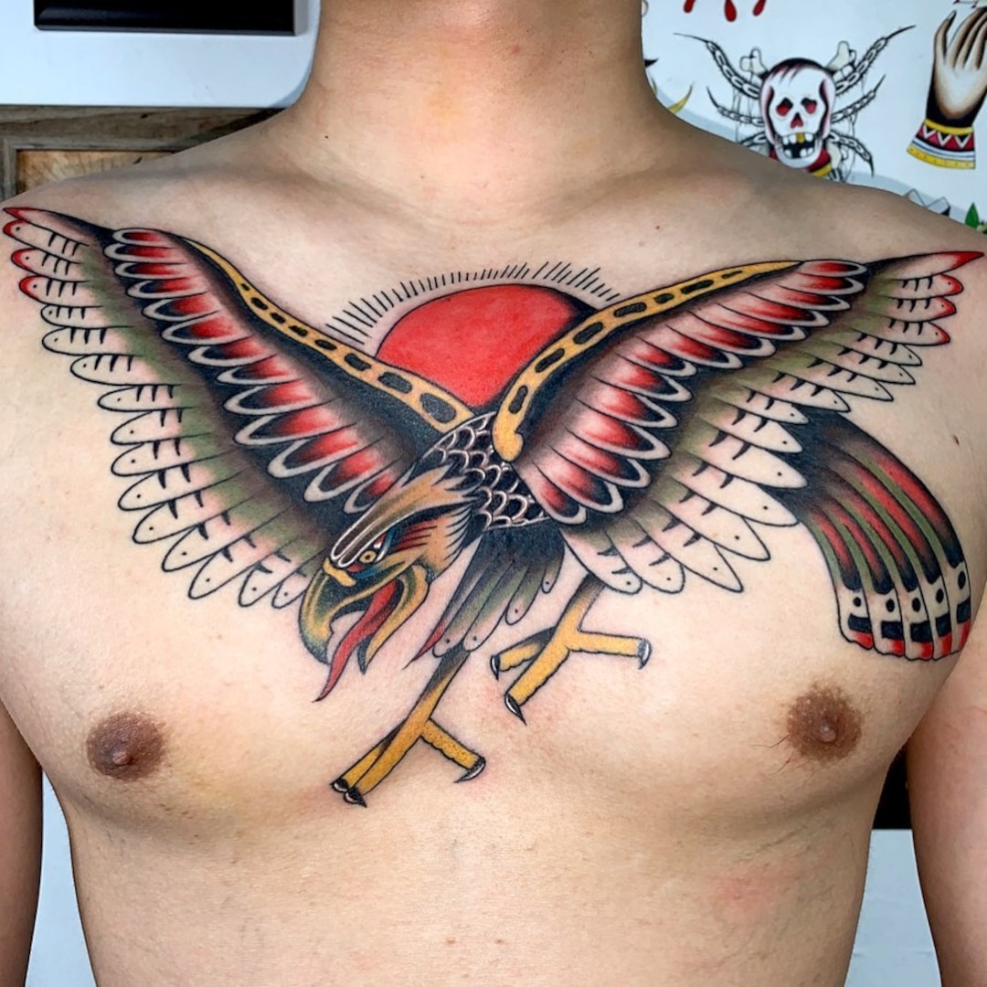 Colorful eagle tattoo on chest with sun background