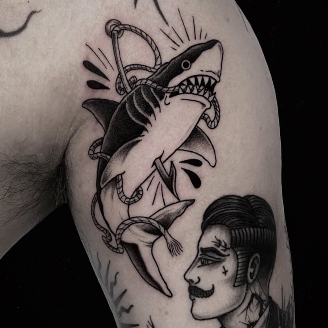 Tattoo of a shark wrapped in a rope on a person's arm