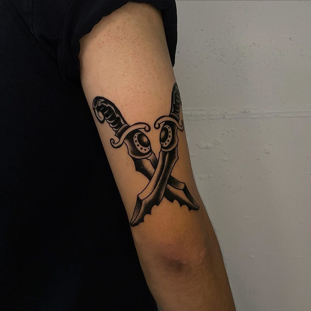Tattoo of crossed swords on a forearm
