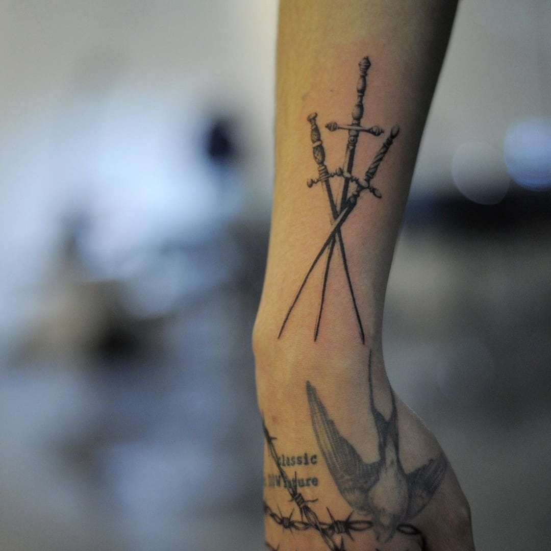 Tattoo of swords on a forearm