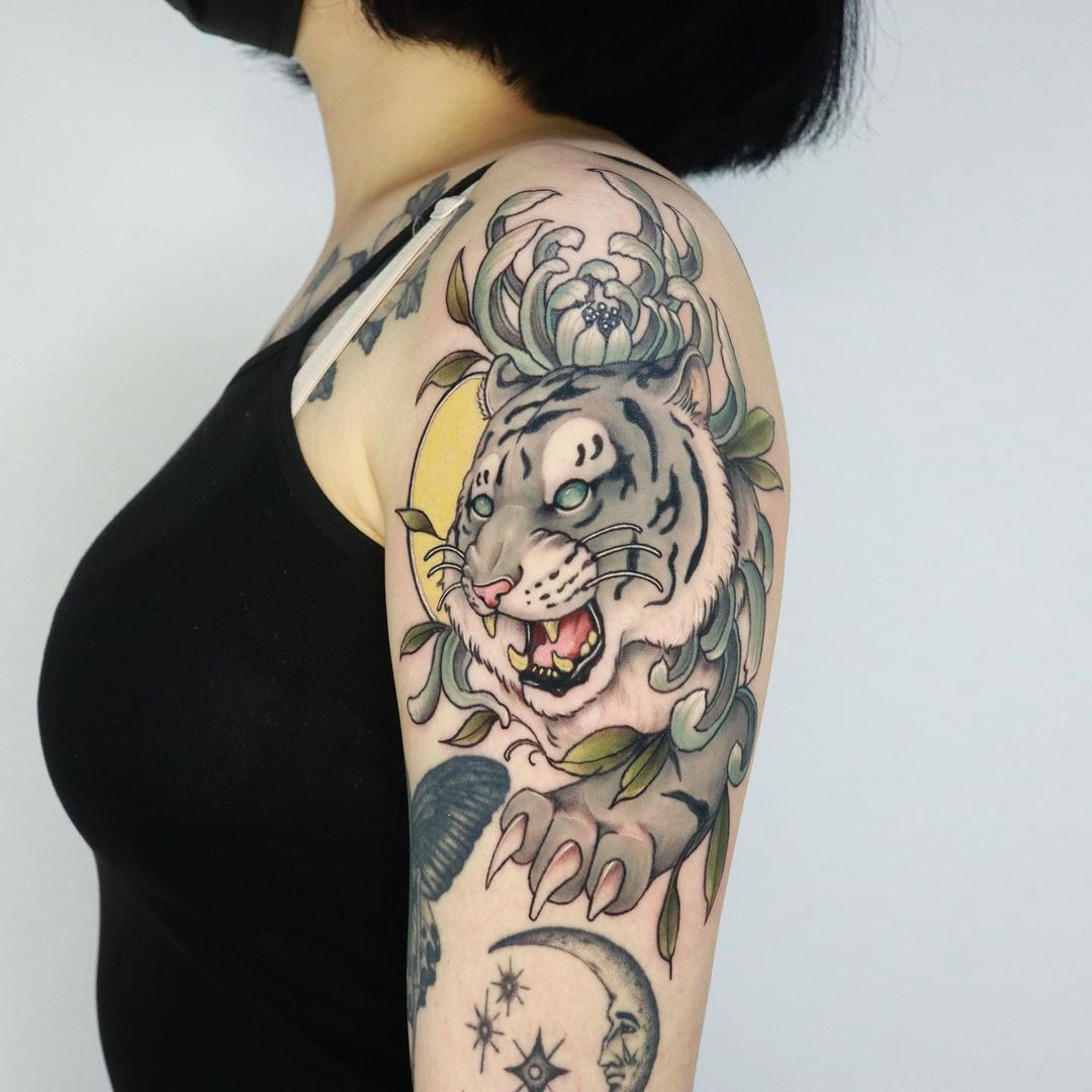 Tattoo of a white tiger on a woman's arm, showcasing vibrant colors and intricate details.