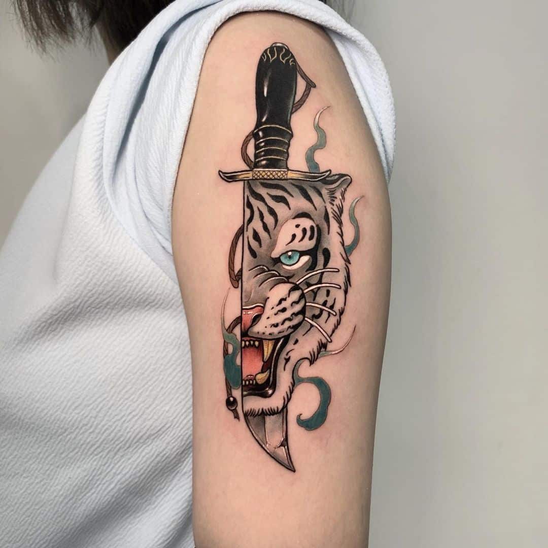 Tattoo of a fierce tiger head with a dagger