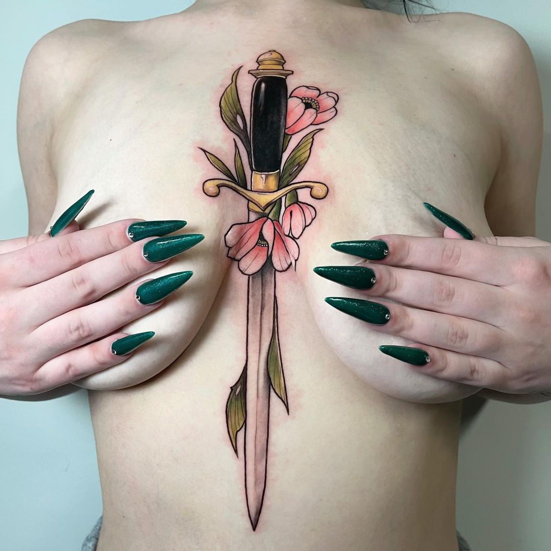 Tattoo of a dagger surrounded by flowers on skin