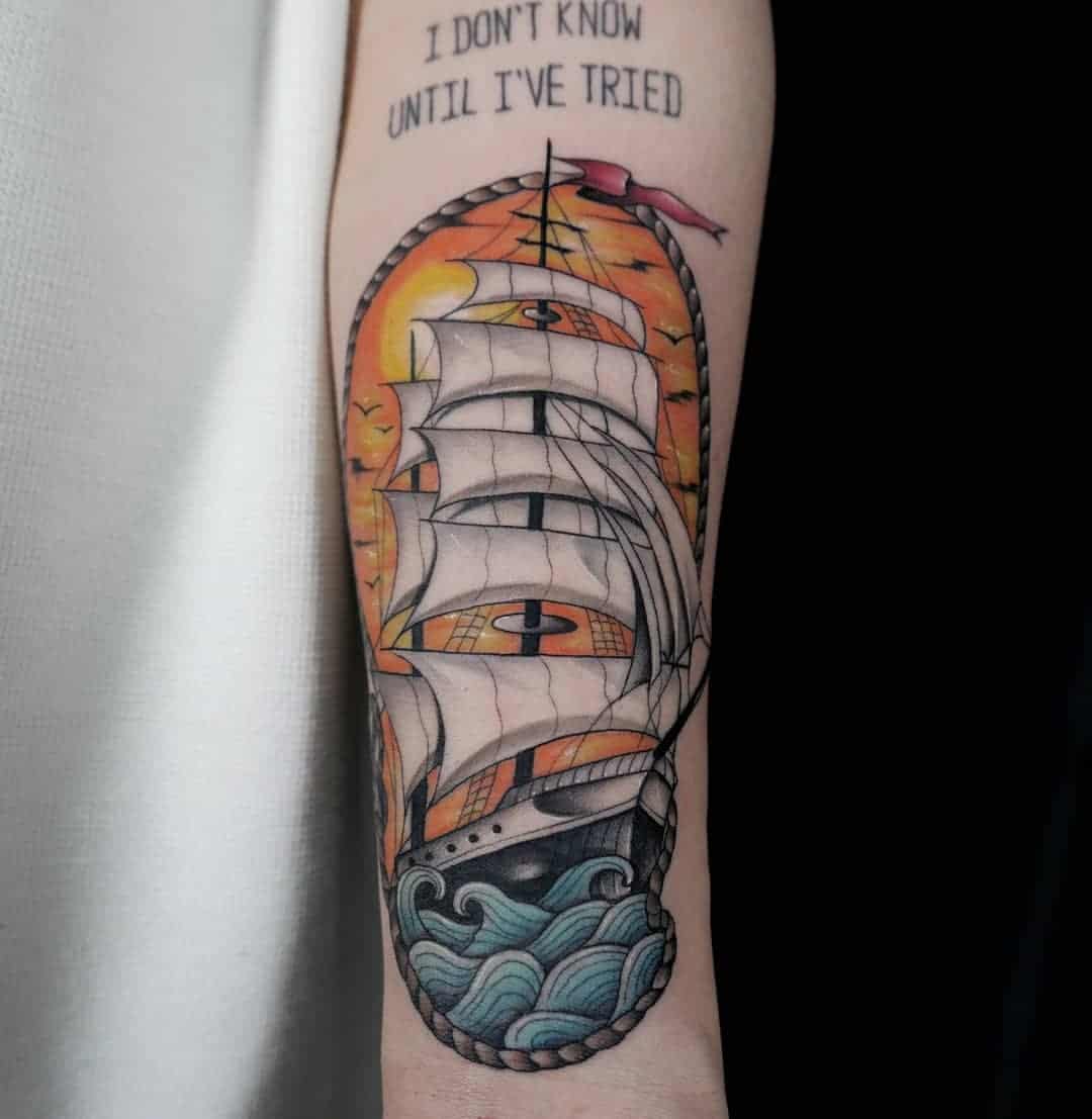 Tattoo of a sailing ship on a bare arm with waves
