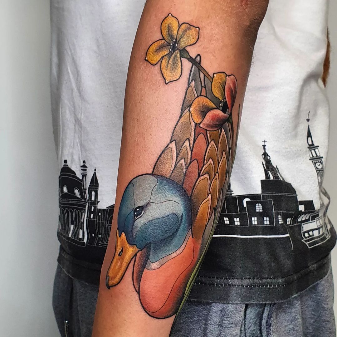 Colorful tattoo of a duck with flowers on an arm.